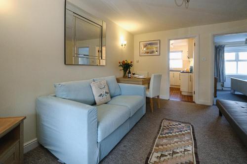 a living room with a blue couch and a table at 1 Coastguard Court in Aldeburgh