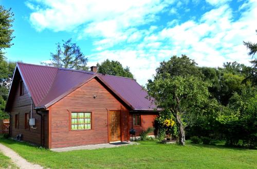 een klein houten huis met een rood dak bij Smolniki 28 in Smolniki