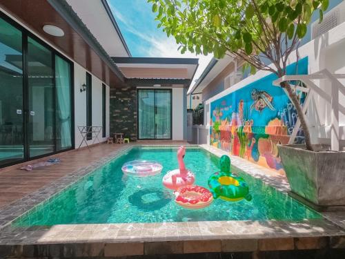a swimming pool with two rubbericans in a house at วาญ่า พูลวิลล่า สัตหีบ in Ban Khlot