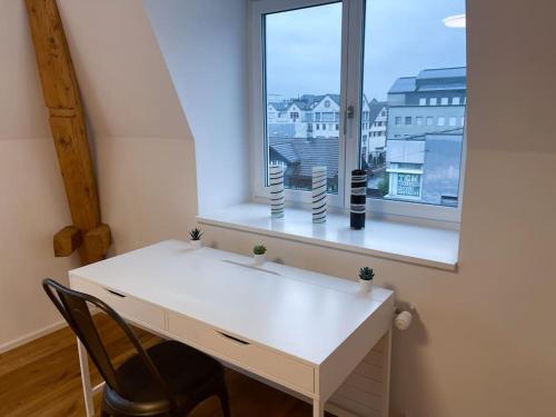 een wit bureau met een stoel voor een raam bij Schlossappartement Rapperswil in Rapperswil-Jona