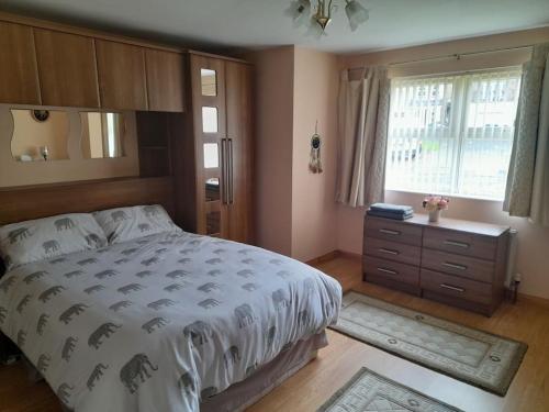 a bedroom with a bed and a dresser and a window at THE LAKE HOUSE: a delightful and peaceful retreat. in Derrymacash