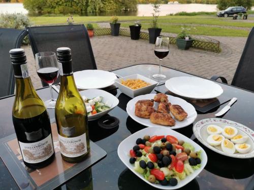 a table with plates of food and two bottles of wine at THE LAKE HOUSE: a delightful and peaceful retreat. in Derrymacash