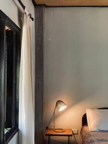 a bedroom with a bed and a lamp on a table at Little Eden Guesthouse in Pang Mapha