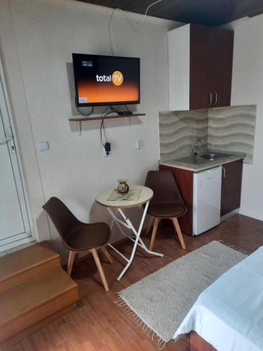 a room with a table and chairs and a tv on the wall at Apartmani Teodora in Nov Dojran