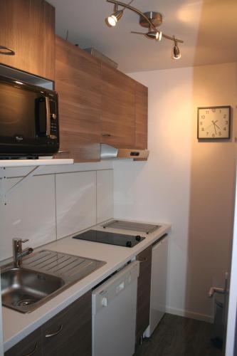 une cuisine avec un évier et un micro-ondes dans l'établissement Appartement Courchevel 1650 pied des pistes, à Courchevel
