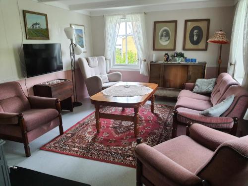 uma sala de estar com cadeiras cor-de-rosa e uma mesa em Hov Feriehus em Gimsøy