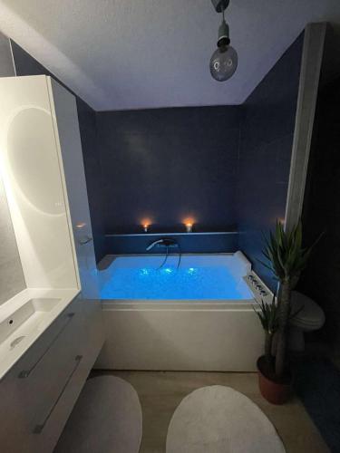 La salle de bains est pourvue d'une baignoire bleue et d'un lavabo. dans l'établissement Sublime appartement avec balneo, à Toulouse