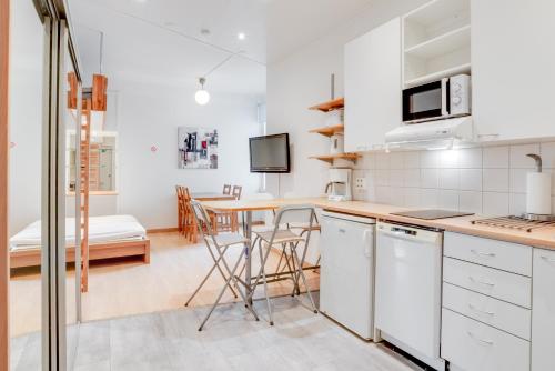 uma cozinha com armários brancos e uma mesa com cadeiras em Orchid&Sakura studios Kamppi em Helsinque