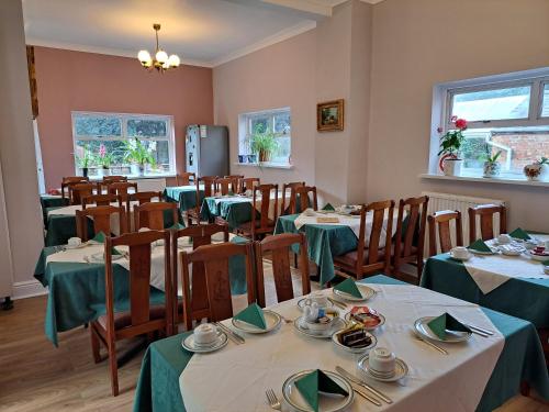 a dining room with tables with green tablecloths at Diamond House in Rugby