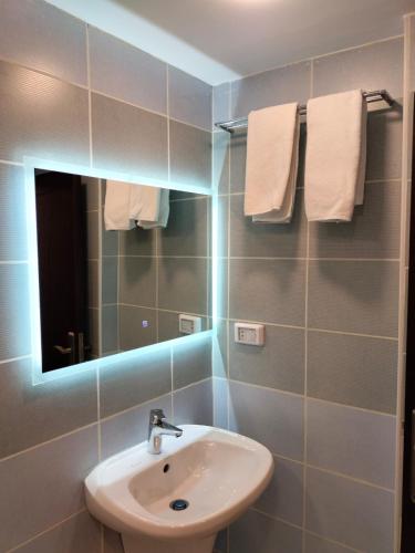 a bathroom with a sink and a mirror and towels at Old Street Apartment in Wadi Musa