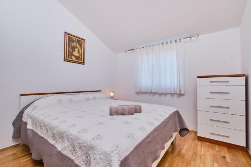 a white bedroom with a bed and a dresser at Appartment Ksenija 1 in Mali Lošinj