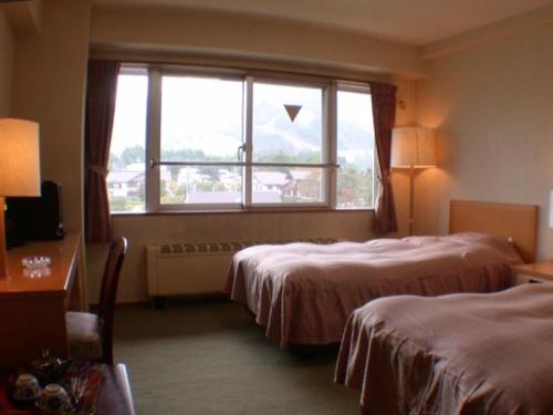 um quarto de hotel com duas camas e uma janela em Mountside Jodel em Hakuba