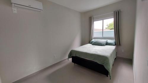 um pequeno quarto com uma cama e uma janela em 1- MAHALO - Aloha Bratz Apartments em Palhoça