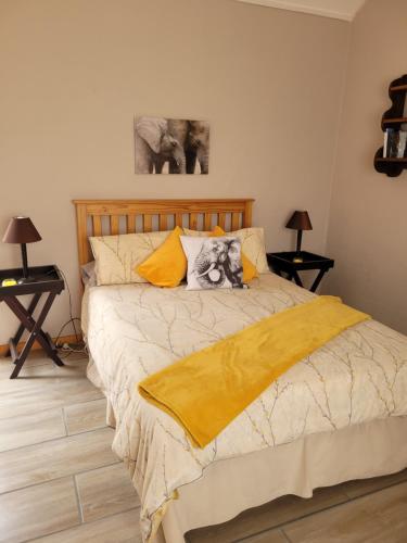 um quarto com uma cama com um cobertor amarelo em Daisy cottage em Robertson
