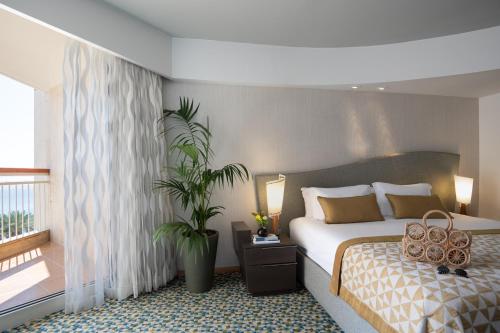 a bedroom with a bed with a plant and a balcony at Dan Eilat Hotel in Eilat