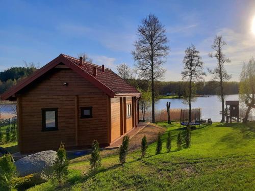 a small wooden cabin on the side of a lake at Domek Letniskowy w Tumianach in Tumiany