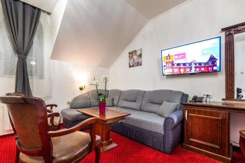 a living room with a couch and a tv at Garni Hotel Royal Crown in Subotica