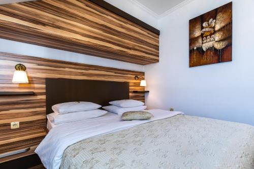 a bedroom with a large bed with a wooden wall at Garni Hotel Royal Crown in Subotica