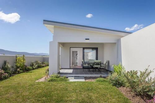a white house with a patio and a table at Benguela Cove - Coastal Retreat in Hermanus