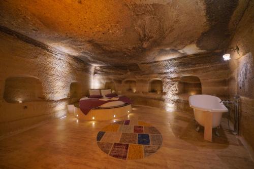 um quarto com uma cama e uma banheira numa gruta em Göreme Cave Lodge em Goreme