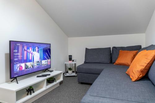 a living room with a couch and a flat screen tv at The Eldern - Spacious, Netflix, free Parking, close to A1 in Peterborough