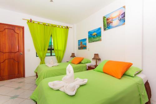 a room with two green beds with towels on them at The Island Home in Puerto Ayora
