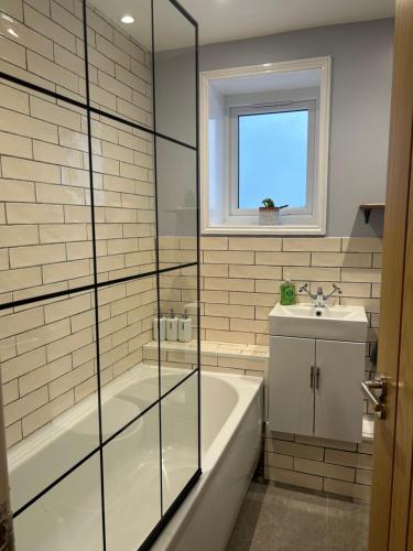 a bathroom with a tub and a sink at Heart of Falmouth - Entire Studio Apartment in Falmouth