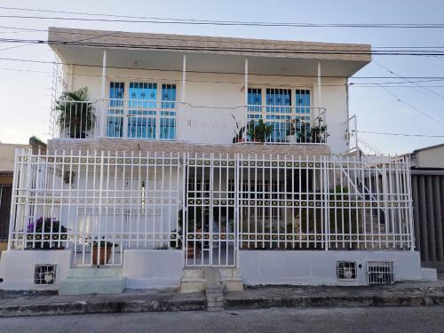 ein weißes Haus mit einem Tor davor in der Unterkunft HABITACION CERCA DE LA UNIVERSIDAD DEL Sinu in Cartagena de Indias