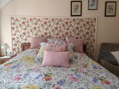 - une chambre dotée d'un lit avec un couvre-lit floral dans l'établissement Jánosi Vendégház, à Tiszafüred