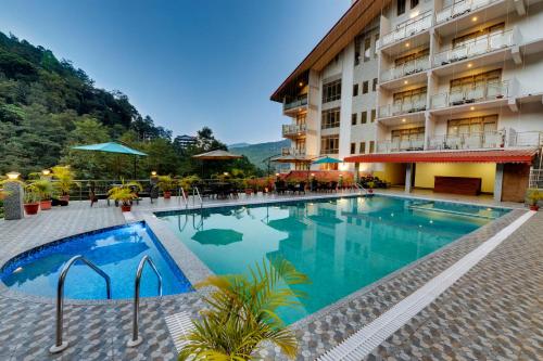 a hotel with a swimming pool in front of a building at Yashshree Kanishka in Gangtok