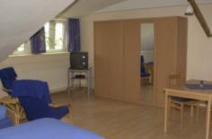 a room with blue chairs and a table and a tv at Reiterhof Könning in Freren