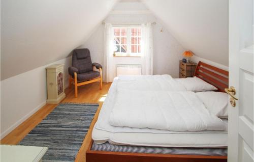 a bedroom with a large white bed and a chair at Amazing Home In Sams With Wifi in Nordby