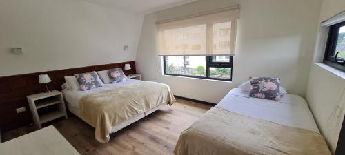 1 dormitorio con 2 camas y ventana en Patagonia Route Apartments en Puerto Varas