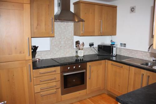 cocina con armarios de madera y encimera negra en Telford Escape en Elgin