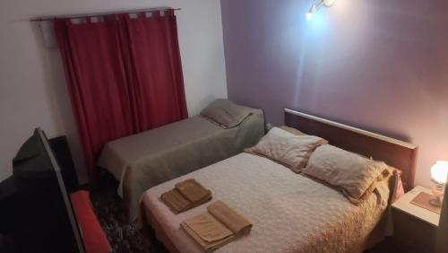 Habitación pequeña con 2 camas y cortina roja. en Departamento La Argentina en San Luis