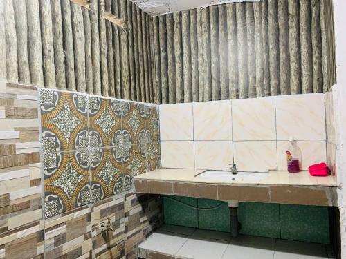 a bathroom with a sink and a tiled wall at MOSS HEDERA HIDE CHALET in Melaka