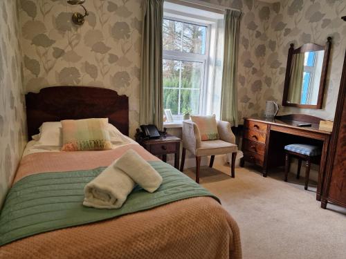 a bedroom with a bed and a desk and a window at Balcary Bay Country House Hotel in Auchencairn