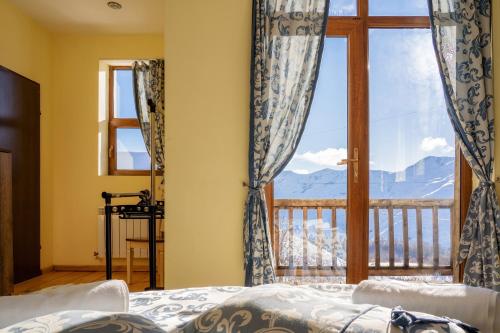 a bedroom with a window with a view of mountains at Snow Time Cottage in Gudauri
