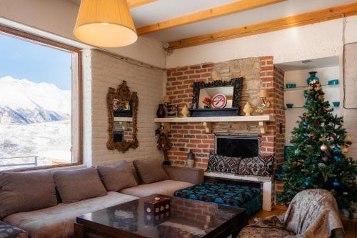 una sala de estar con un árbol de Navidad y una chimenea en Snow Time Cottage, en Gudauri