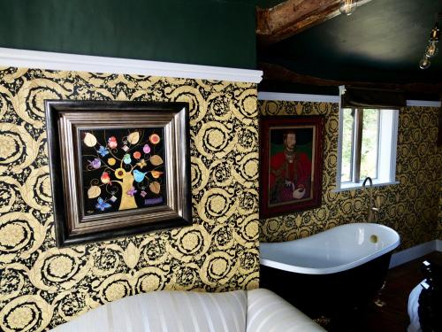 baño con bañera y una pintura en la pared en Captivating 9-Bed House Hot Tub Near Cambridge, en Saffron Walden