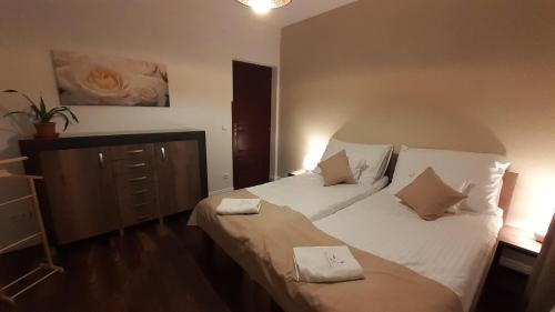 a bedroom with a bed with white sheets and pillows at Bíbic Apartman A in Kápolnásnyék