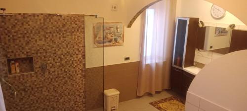 a bathroom with a shower and a clock on the wall at Domos Le Due Tuie in Piscinas