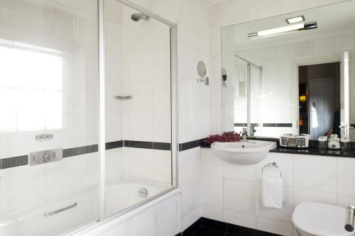 a white bathroom with a shower and a sink at Grange Beauchamp Hotel in London