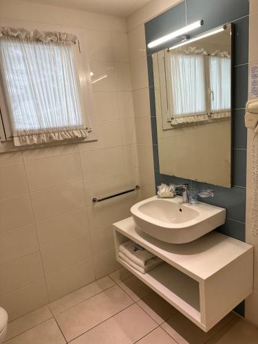 a white bathroom with a sink and a mirror at Hotel Albatros 3 Stelle Superior in Lido di Jesolo
