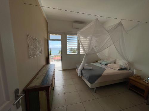 - une chambre avec un lit et une moustiquaire dans l'établissement Maison avec piscine à 80 mètres de la plage, au Diamant
