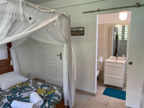 - une chambre avec un lit à baldaquin et une salle de bains dans l'établissement Maison avec piscine à 80 mètres de la plage, au Diamant
