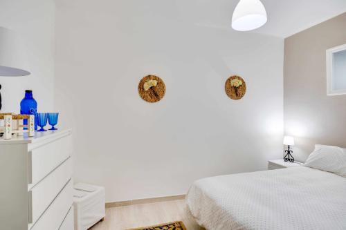 a white bedroom with a bed and blue glasses on the wall at Casa da Avó Maria in Arraiolos