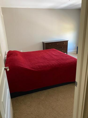 um quarto com uma cama vermelha e uma cómoda em Lakefront view private bedroom and bathroom with kitchen em McCordsville
