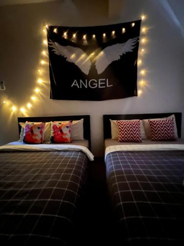 2 camas en una habitación con un signo de ángel en la pared en Room2#IG theme Bargainous#Shared Bathroom#4pax#2min Kek Lok Si en Ayer Itam