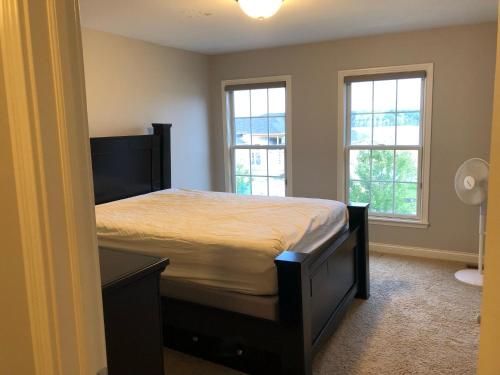 um quarto com uma cama e duas janelas em Lakefront view private bedroom and bathroom with kitchen em McCordsville